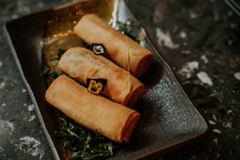Aromatic Duck Spring Rolls on a plate with flowers at Lulu Wild